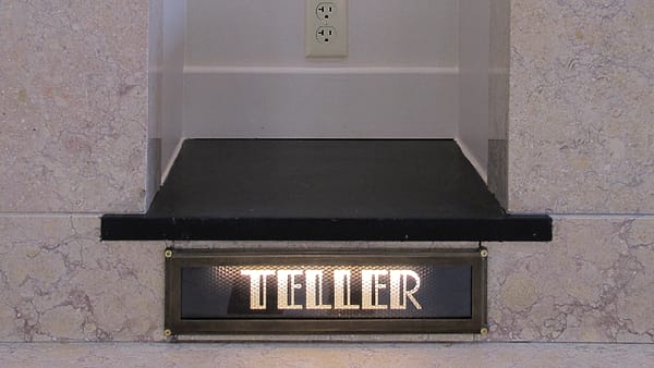A desk tray holding a single sealed envelope beside an open ledger with ruled columns and a fountain pen.