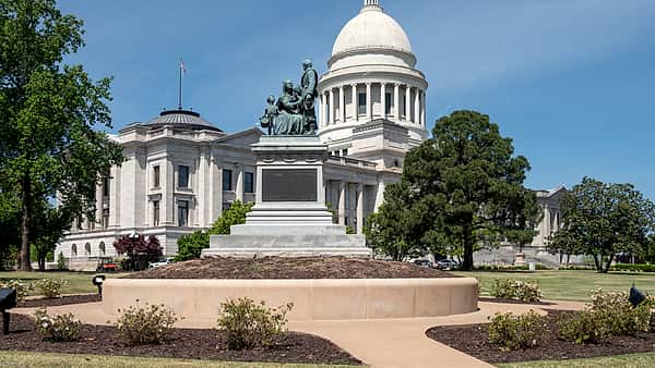 A row of state capitol domes rendered as small brass paperweights lined up along a wooden windowsill in daylight.