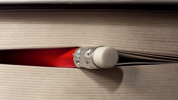A desk calendar with two weeks visible, a pen resting across it and a coffee cup leaving a ring on the page.