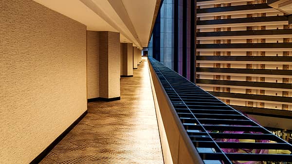 A glass-walled meeting room seen from a corridor, with an empty chair at the head of a long table.