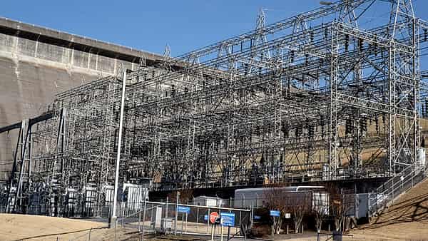 A partly built concrete structure surrounded by scaffolding and a tower crane against a pale overcast sky