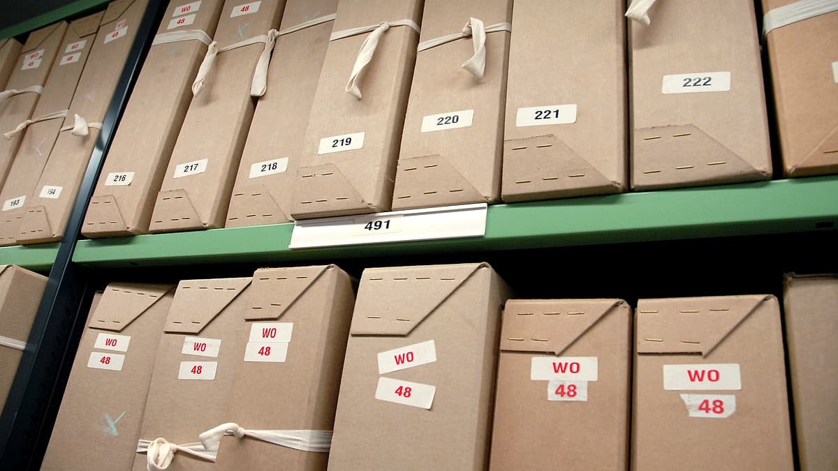 Numerous paper file folders arranged in overlapping rows across a large table, edges fanned out