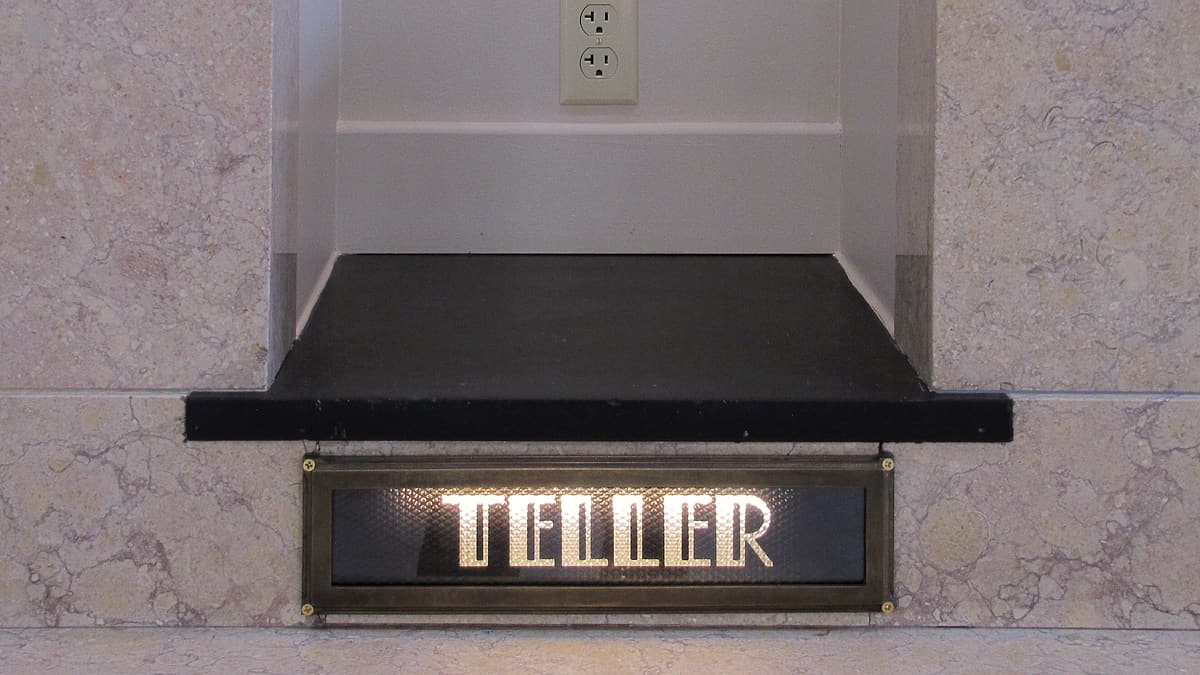 A desk tray holding a single sealed envelope beside an open ledger with ruled columns and a fountain pen.
