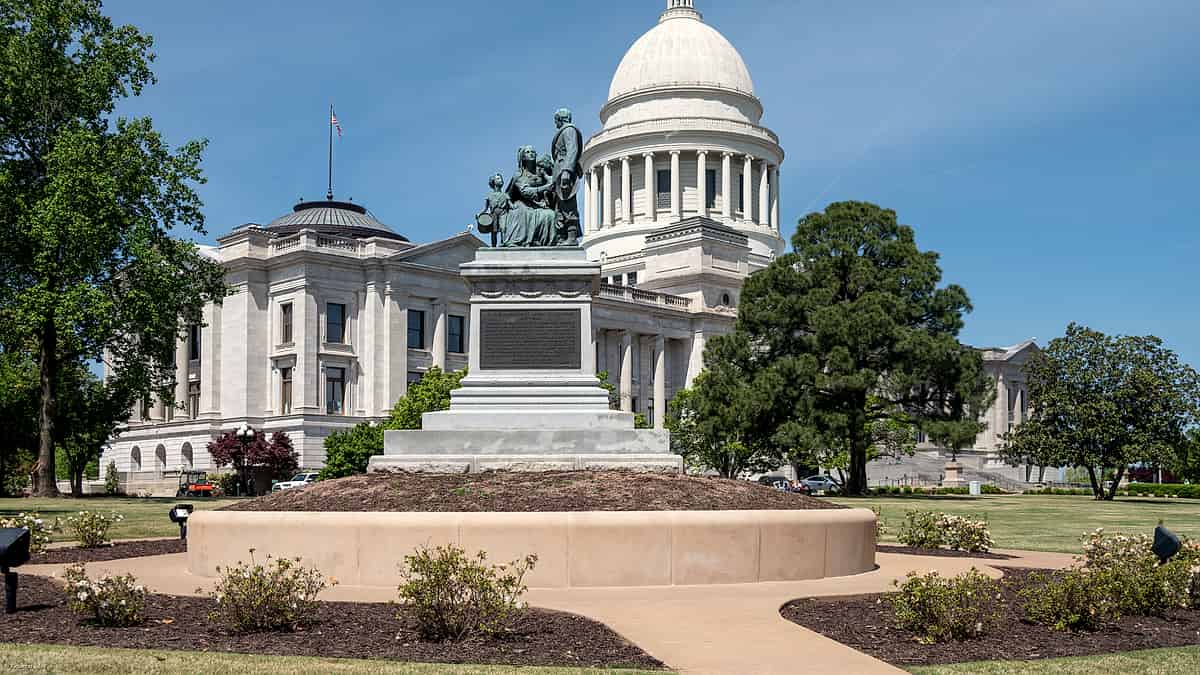 A row of state capitol domes rendered as small brass paperweights lined up along a wooden windowsill in daylight.