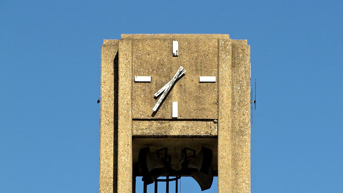 A wall calendar with a single square circled in red hanging beside a hard hat on a plain painted wall